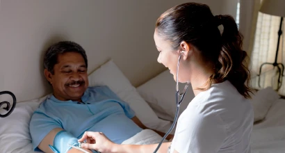 Doctor measuring blood pressure of senior patient lying in bed